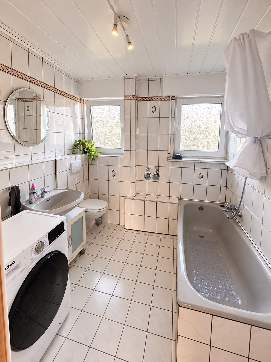 Badezimmer mit Badewanne und Waschtrockner