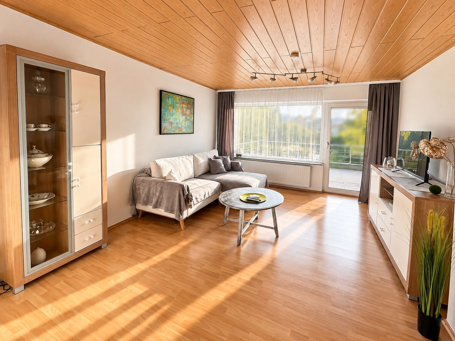 Sonniges Wohnzimmer mit Ecksofa und Tür zur Terrasse