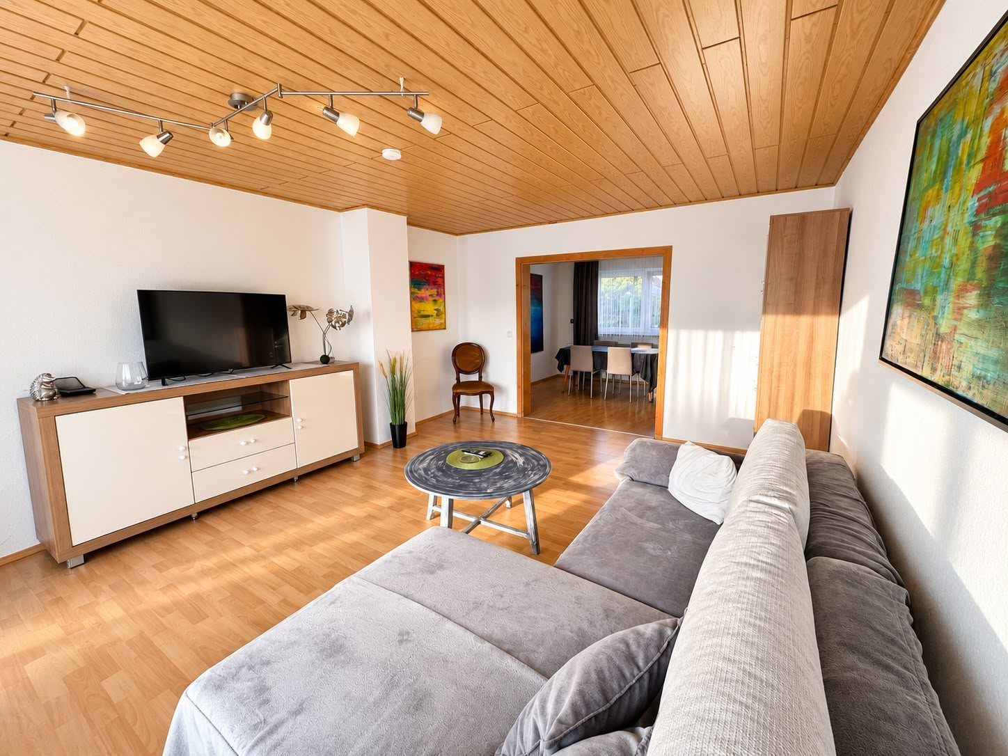Wohnzimmer mit Sofalandschaft, TV und Blick in den Essbereich